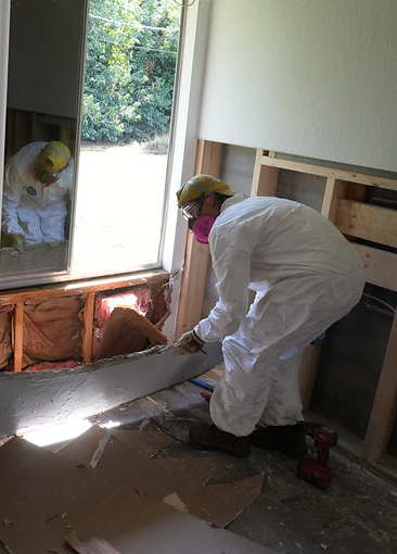 AmeriCorps member in haz mat suit working in house on insulation