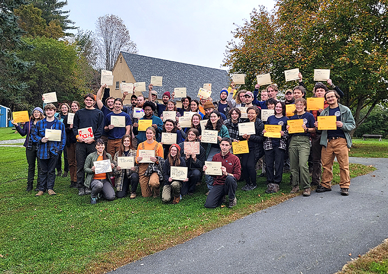 large group of young adults, AmeriCorps members, standing together and holding signs "I serve"