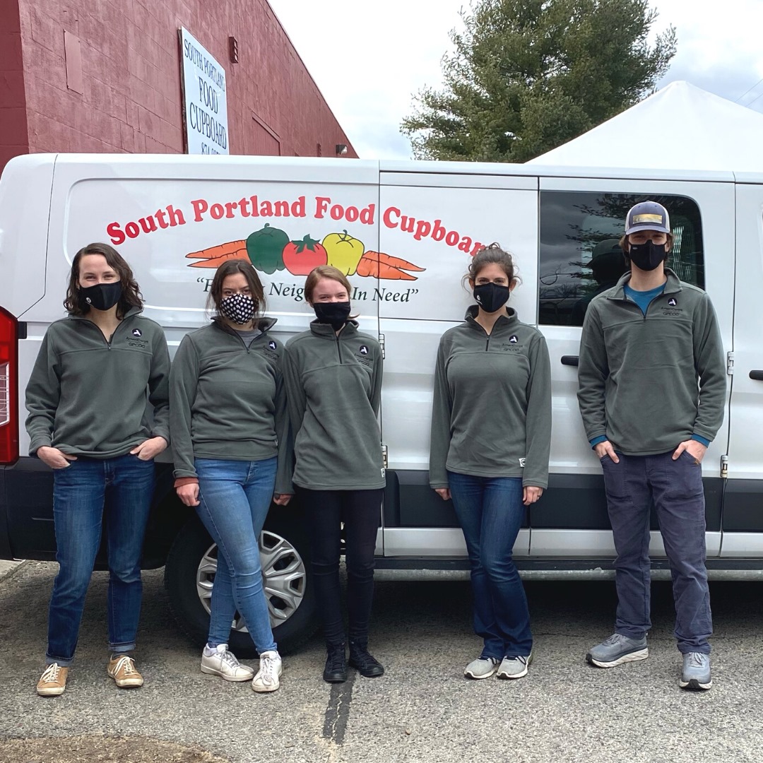 Five individuals stand in front of a bus