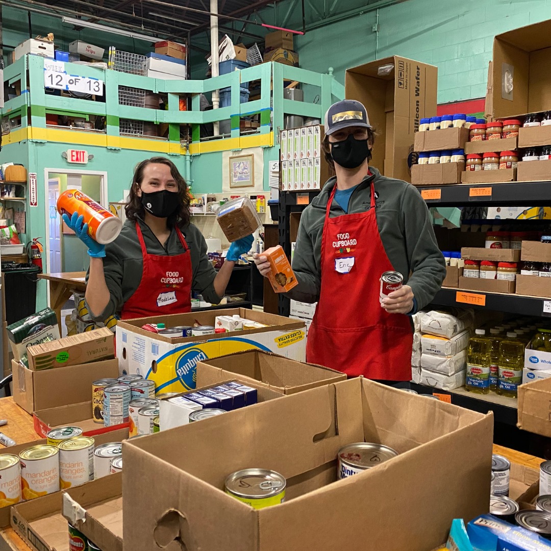 two individuals box food in a warehouse
