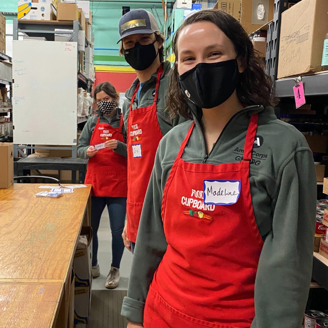 Three individuals pose for a photo in a warehouse