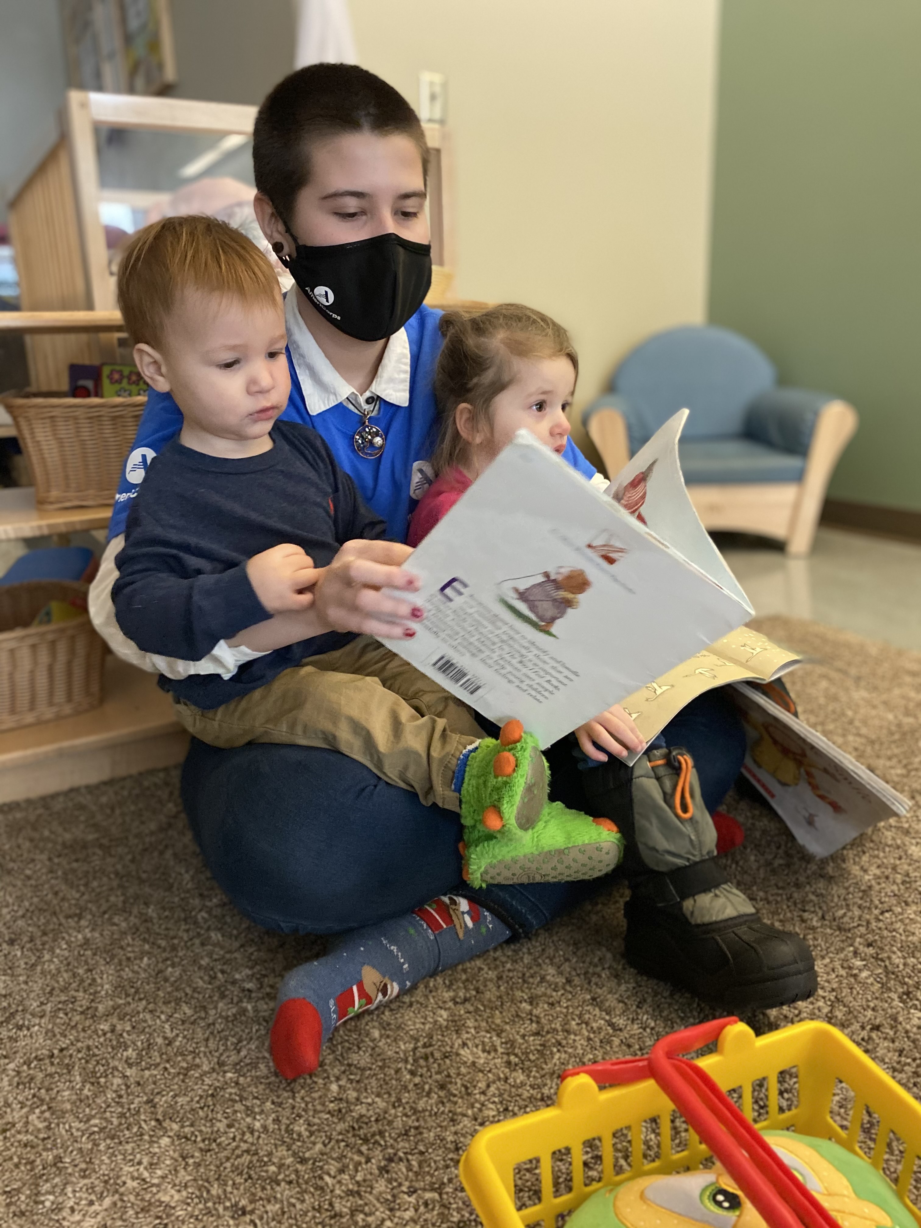 Teacher reads a book to several students in a classroom