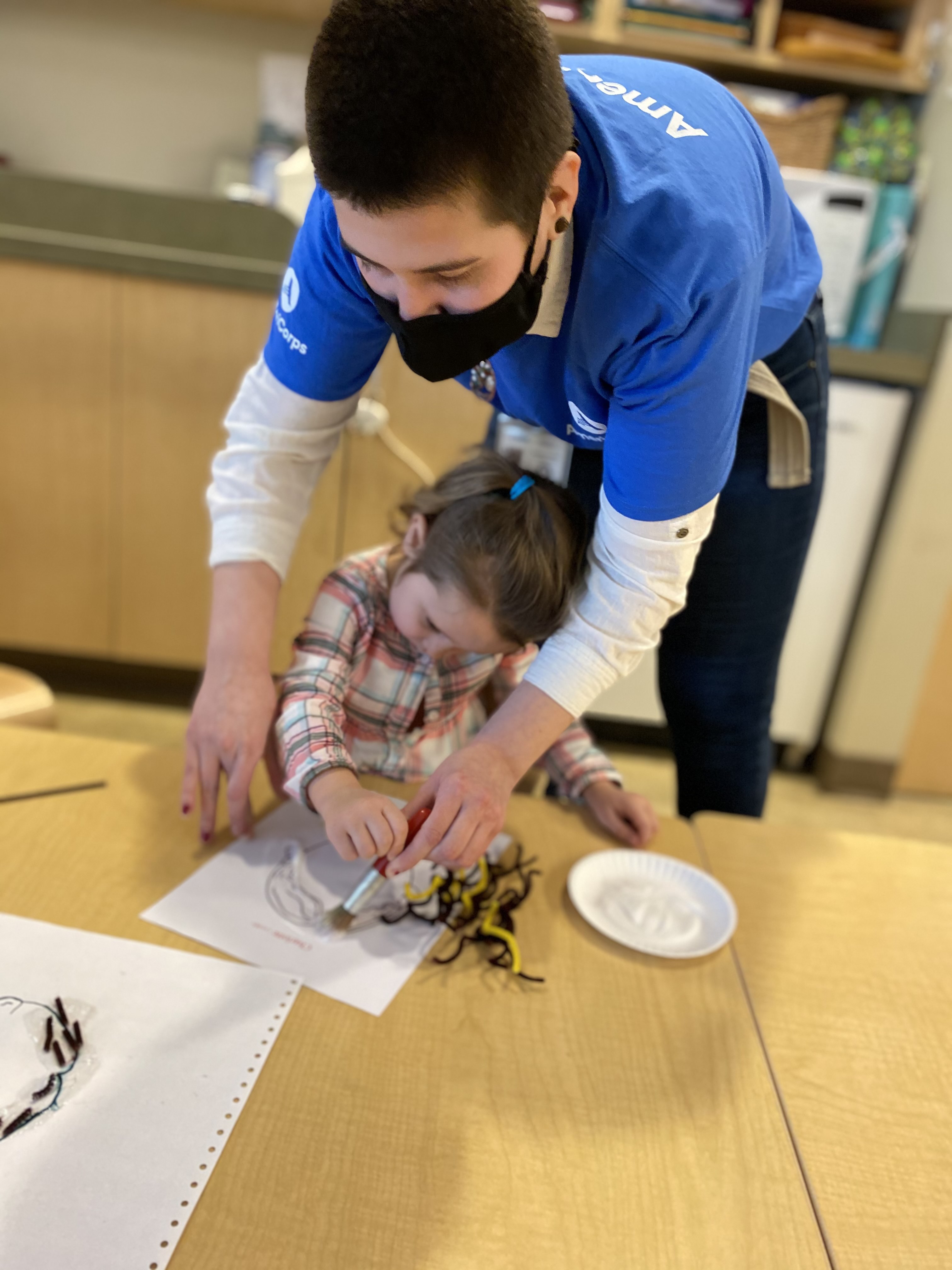 Teacher helps student color in a classroom