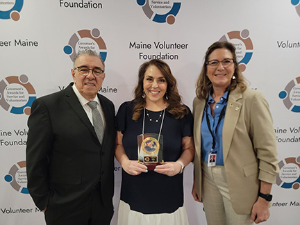 Fortin standing with her award between Maine Volunteer Foundation president, John Portela, and General Dunn.